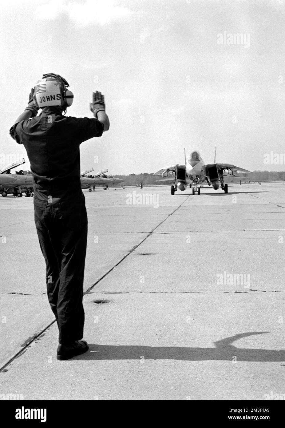 Un membre de l'équipage au sol dirige un avion F-14A Tomcat du Fighter Squadron 32 (VF-32) en taxi sur la ligne de vol après son arrivée à la base. Le personnel de l'escadre aérienne Carrier 3 et de l'escadre aérienne Carrier 17 rentre chez lui après avoir servi dans le golfe Persique pendant l'opération tempête du désert. Objet opération/série: TEMPÊTE DU DÉSERT base: Naval Air Station, Oceana État: Virginie (va) pays: États-Unis d'Amérique (USA) Banque D'Images