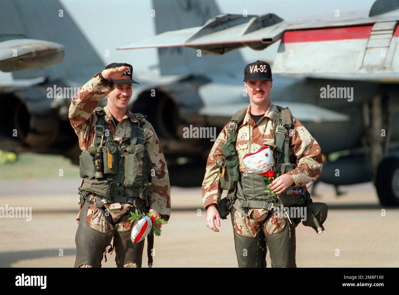 Deux aviateurs de la marine de l'escadron d'attaque 35 (va-35) descendent la ligne de vol vers les amis et les membres de la famille à leur disposition pour les rencontrer. La VF-35 est retournée à Oceana après son déploiement en mer Rouge à bord du porte-avions USS SARATOGA (CV-60) pour l'opération Desert Shield et l'opération Desert Storm. Objet opération/série: DESERT STORMDESERT SHIELD base: Naval Air Station, Oceana État: Virginia (va) pays: Etats-Unis d'Amérique (USA) Banque D'Images