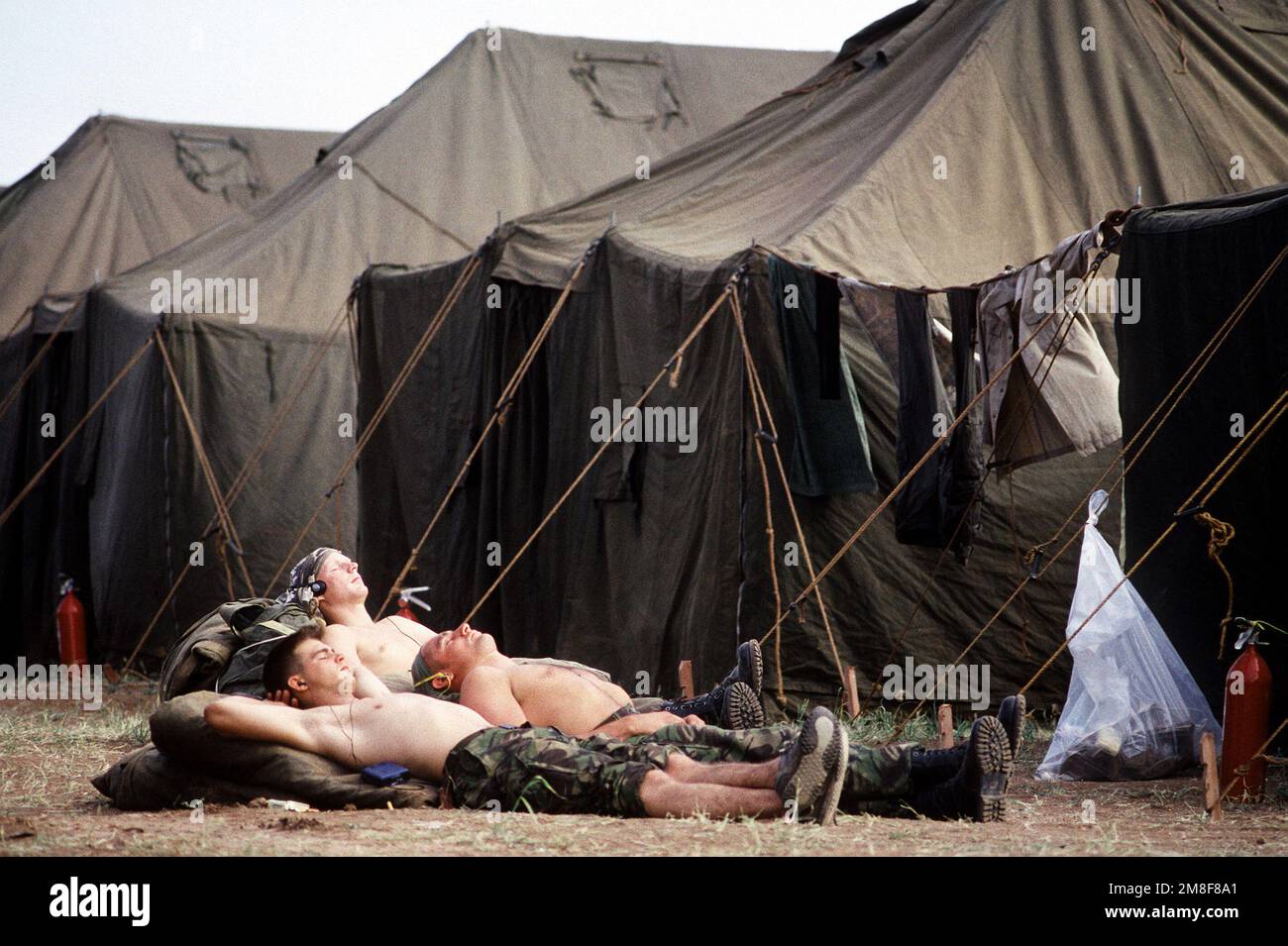 Trois militaires hors service se détendent au soleil entre deux rangées de tentes à la base de soutien des services humanitaires établie pour l'opération fournir confort, un effort multinational pour aider les réfugiés kurdes dans le nord de l'Irak et le sud de la Turquie. Sujet opération/série: FOURNIR LE CONFORT base: Silopi pays: Turquie (TUR) Banque D'Images