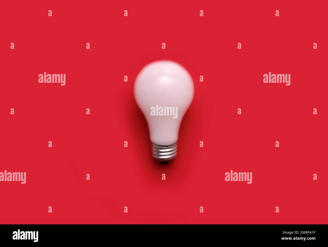 Pose d'une seule ampoule blanche sur fond rouge Banque D'Images