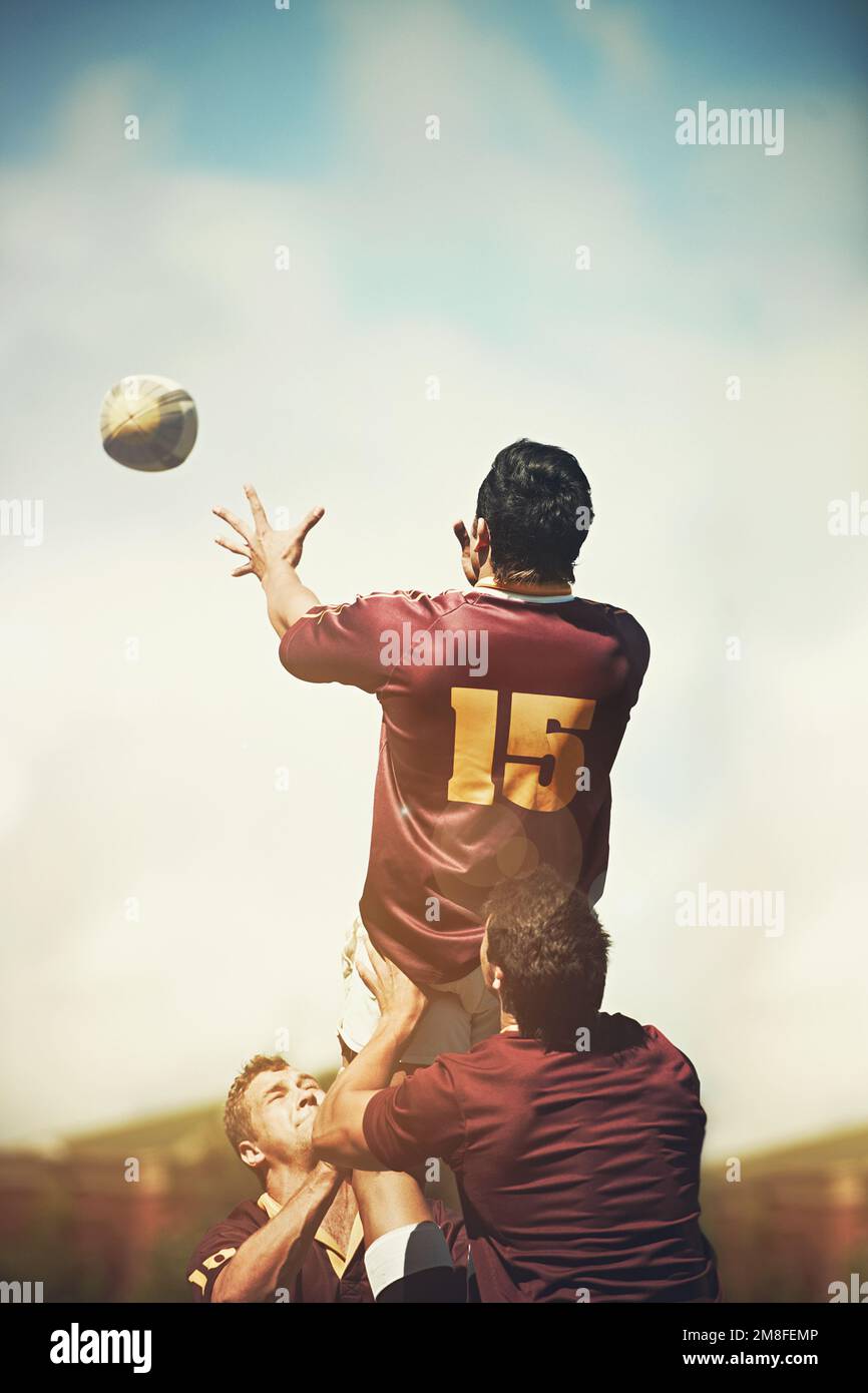 Exécution d'une ligne parfaite. vue arrière d'un jeune joueur de rugby qui attrape le ballon lors d'une mise en ligne. Banque D'Images
