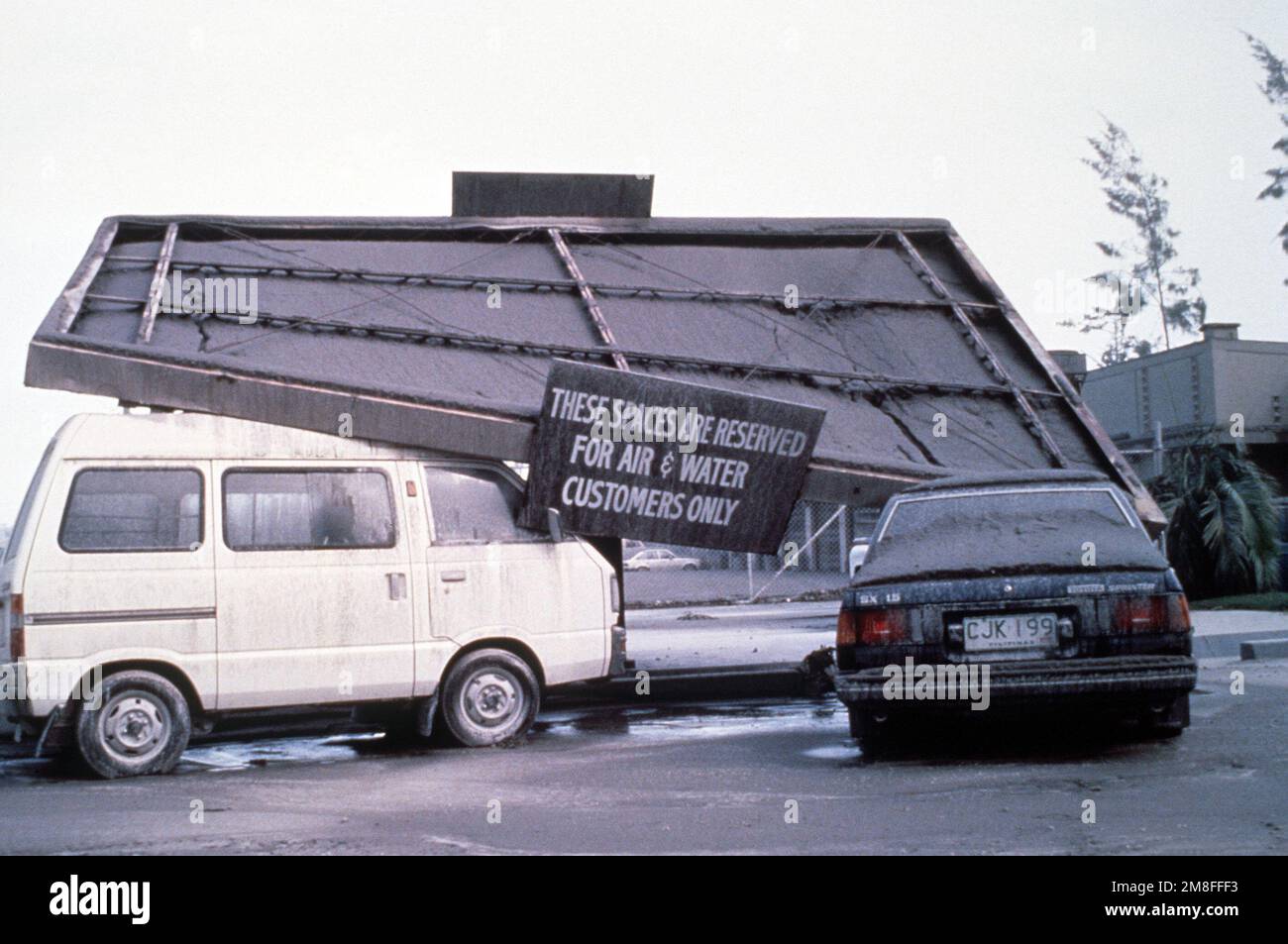 L'auvent d'une station-service est écrasé sur des automobiles sous le poids des quatre pouces de cendres volcaniques qui sont tombées à la suite de l'éruption de 10 juin du mont Pinatubo. Plus de 20 000 personnes évacuées ont été retirées de la région dans le cadre de l'opération Fiery Vigil du notaire américain. Sujet opération/série: BASE DE TIR VIGILE: Clark Air base État: Luzon pays: Philippines(PHL) Banque D'Images