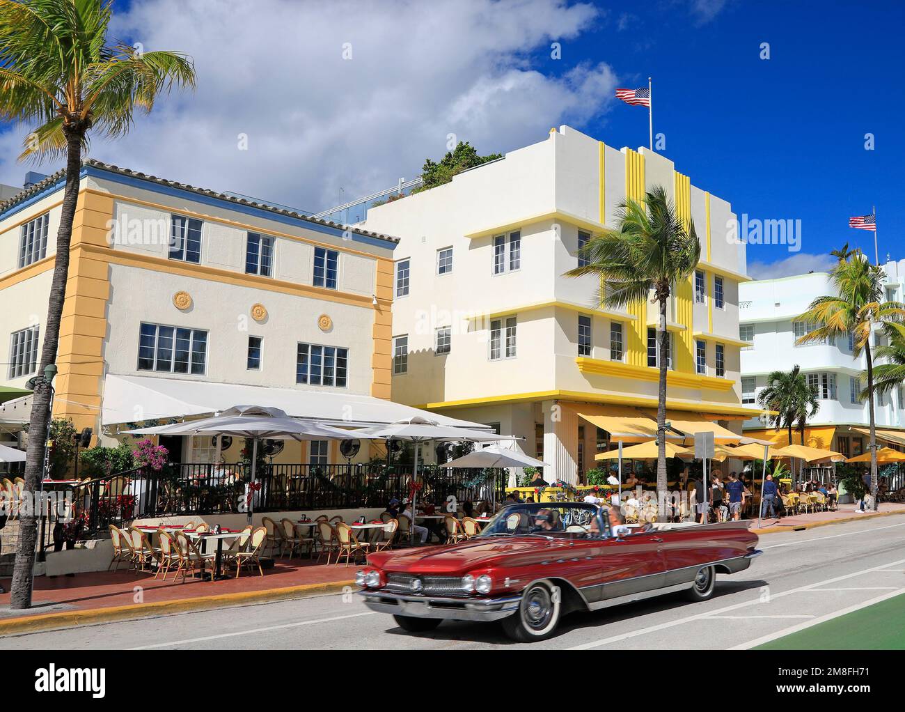 Vibes matinales à Ocean Drive, les touristes utilisant une voiture rouge américaine décapotable classique d'époque dans le quartier historique art déco, Miami Beach Banque D'Images