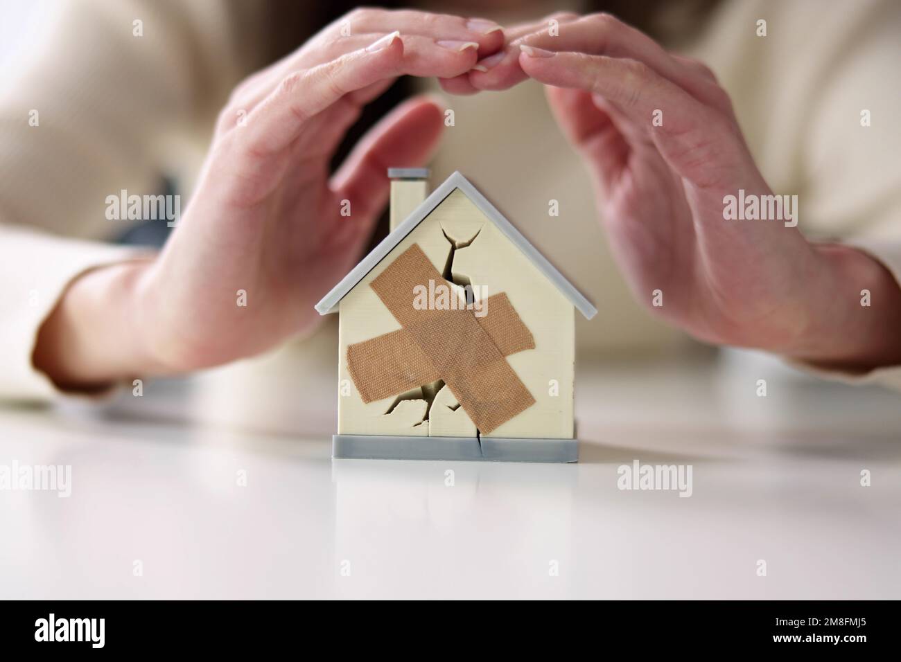 Femme d'affaires protégeant la maison brisée. Dommages immobiliers Banque D'Images