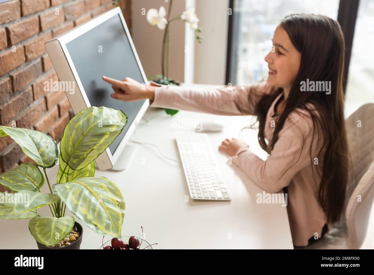 Enseignement à domicile. Une fille est assise à une table avec un ordinateur portable lors d'un chat vidéo en ligne d'une leçon d'école avec un enseignant et une classe. Concept de Banque D'Images
