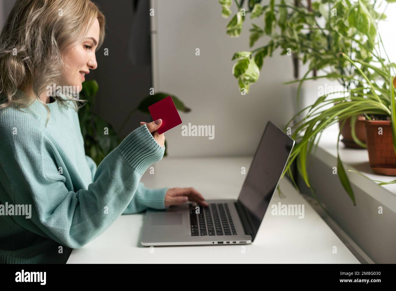 Jeune femme tenant une carte de crédit et utilisant un ordinateur portable. Femme d'affaires ou entrepreneur travaillant à la maison. Achats en ligne, e-commerce, Internet Banque D'Images