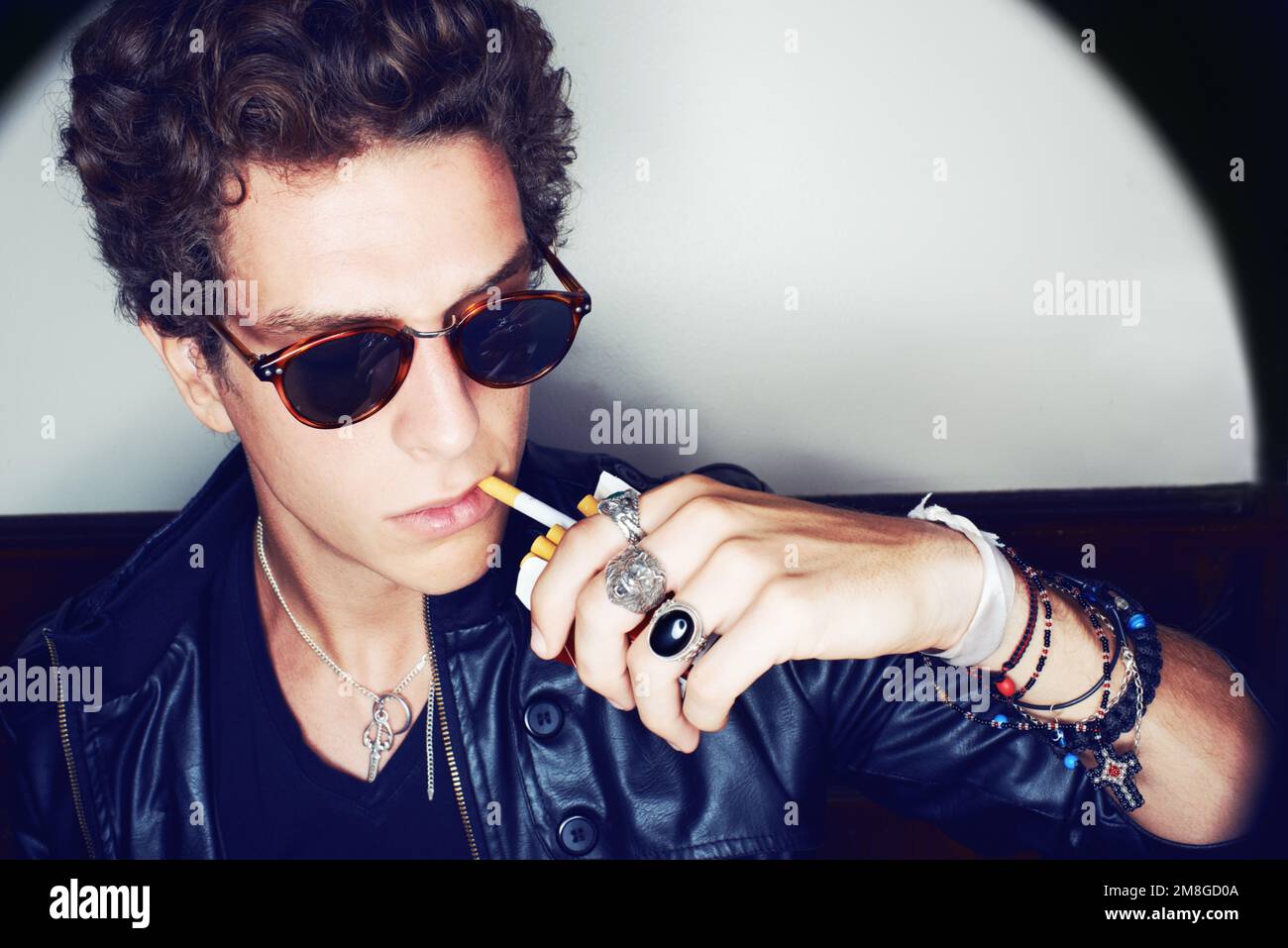 Refroidissement sans effort. Gros plan d'un jeune homme élégant tirant une cigarette hors d'une boîte avec ses lèvres. Banque D'Images