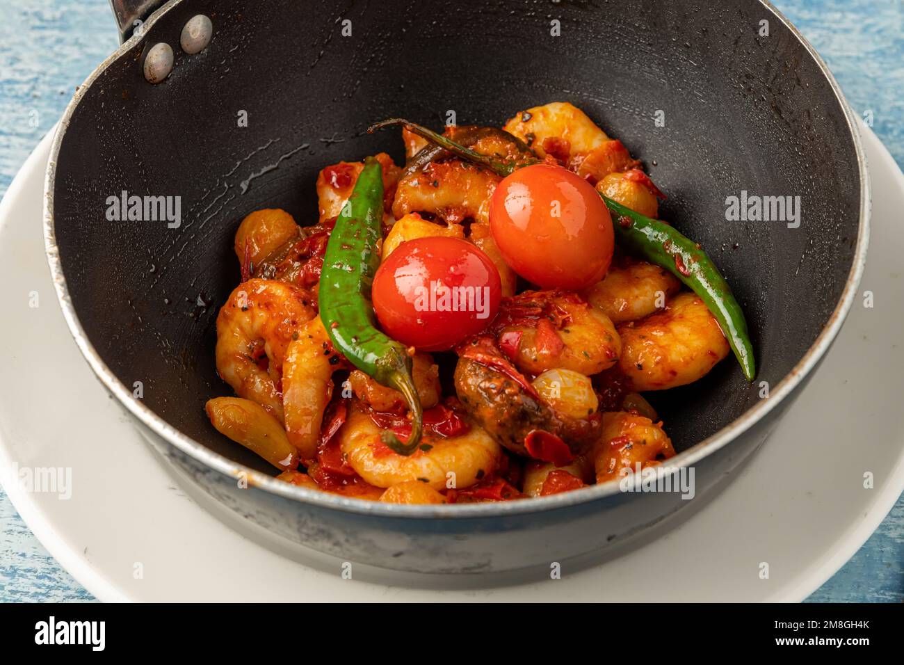 Cocotte de crevettes avec tomates, ail et poivrons dans un wok noir Banque D'Images