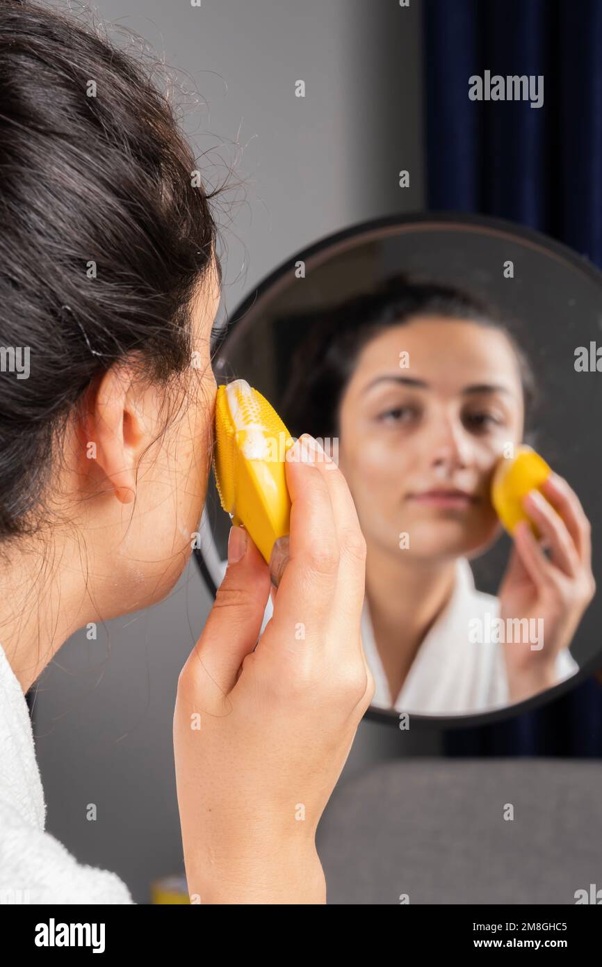 Femme nettoyant la peau, caucasienne brune femme millénaire. À l'aide de mousse et d'éponge. Soin de la peau, concept de beauté image verticale avec espace de copie. Banque D'Images