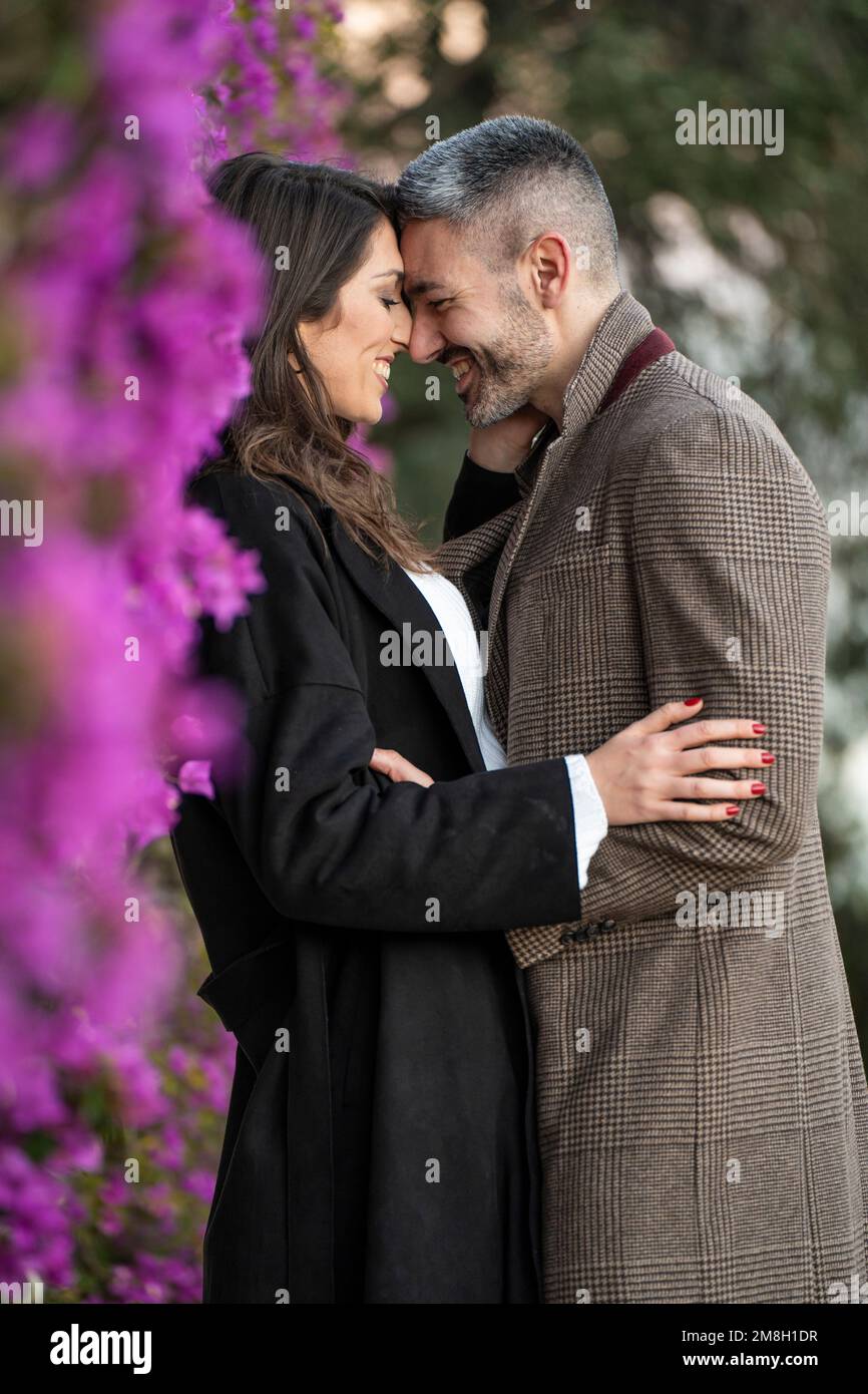 Couple en amour très proche ensemble à côté de quelques fleurs violettes Banque D'Images