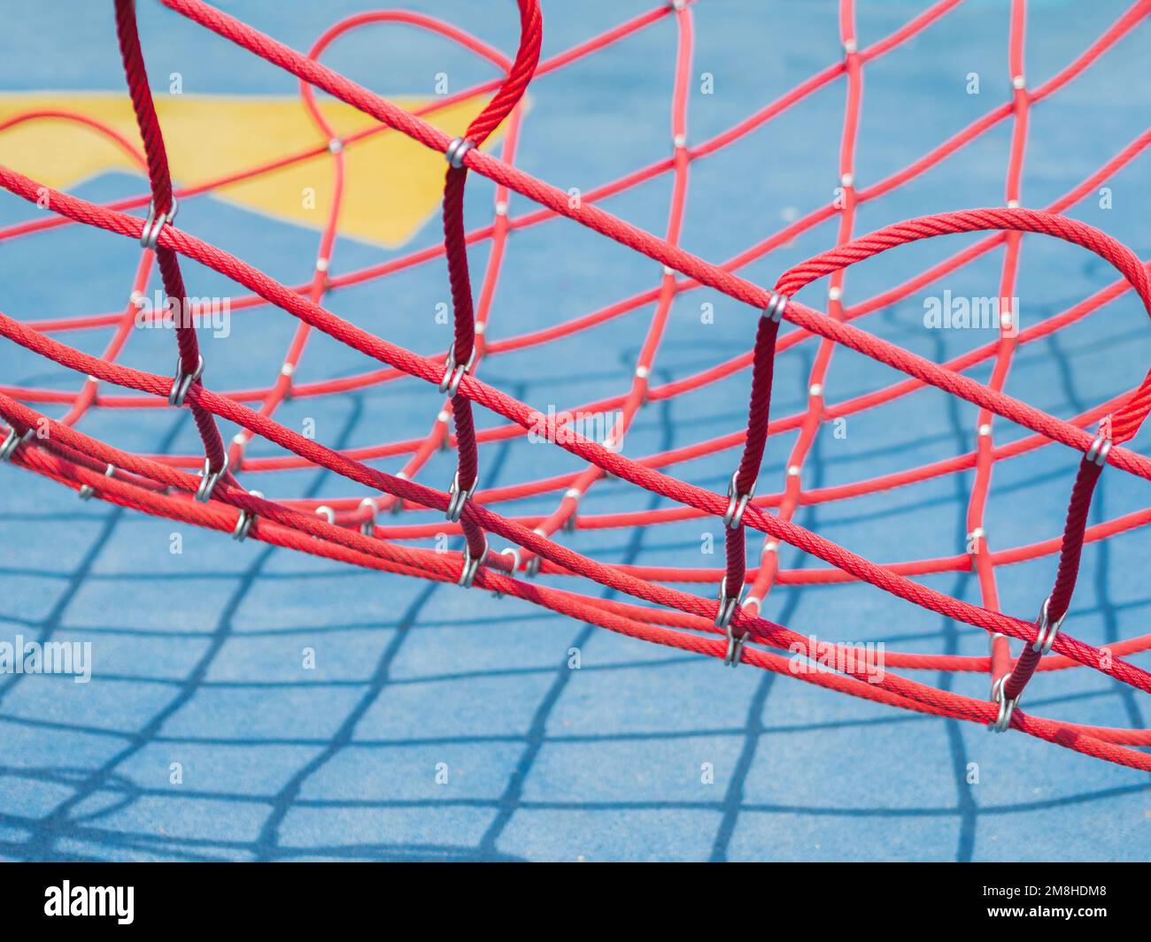 Filet rouge sur fond bleu. Équipement de sport sur le terrain de sport public par beau temps. Ombres géométriques par temps ensoleillé. Banque D'Images