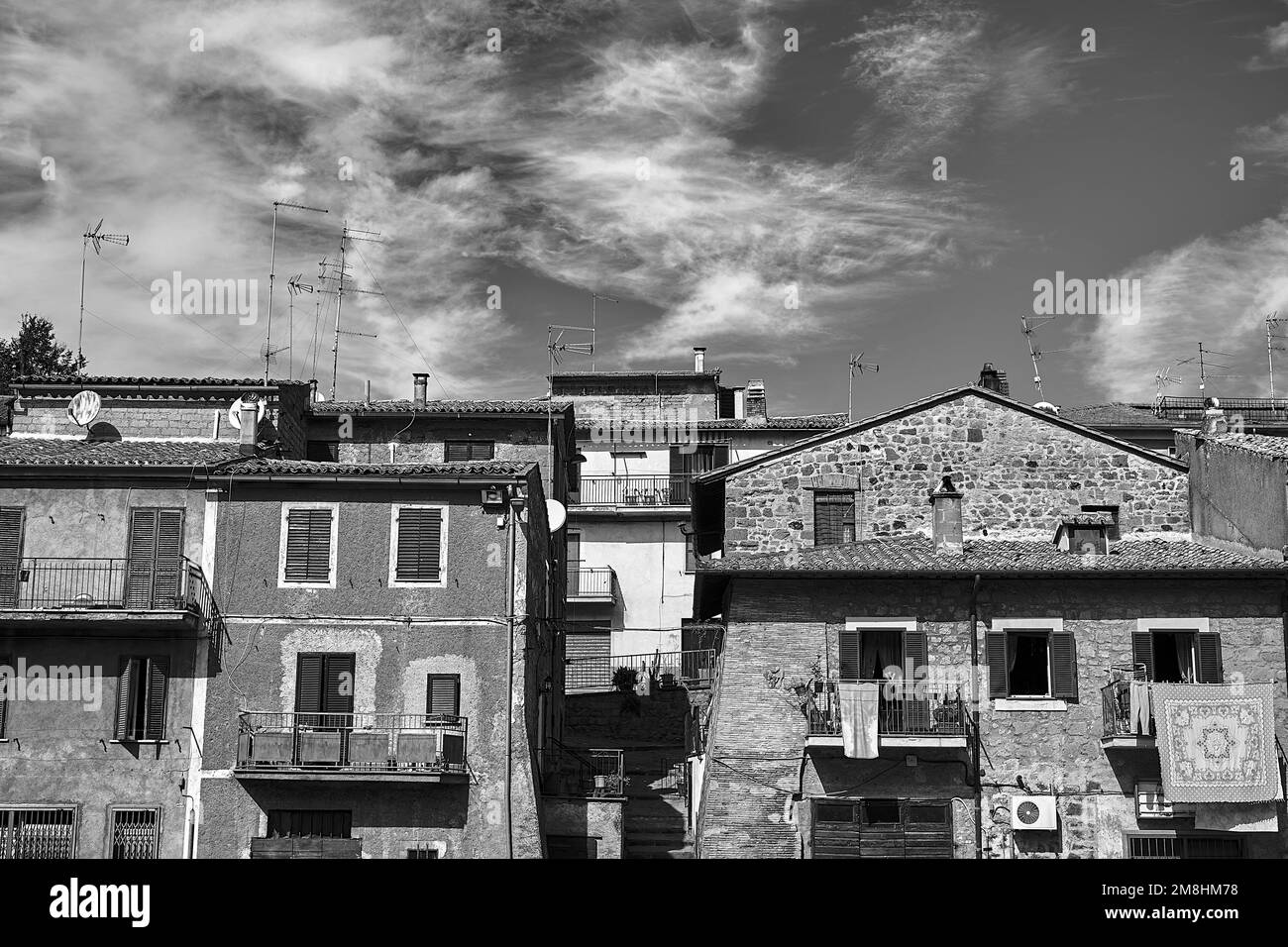 Toits avec antennes et murs avec fenêtres et balcons dans une petite ville de Toscane, Italie, monochrome Banque D'Images
