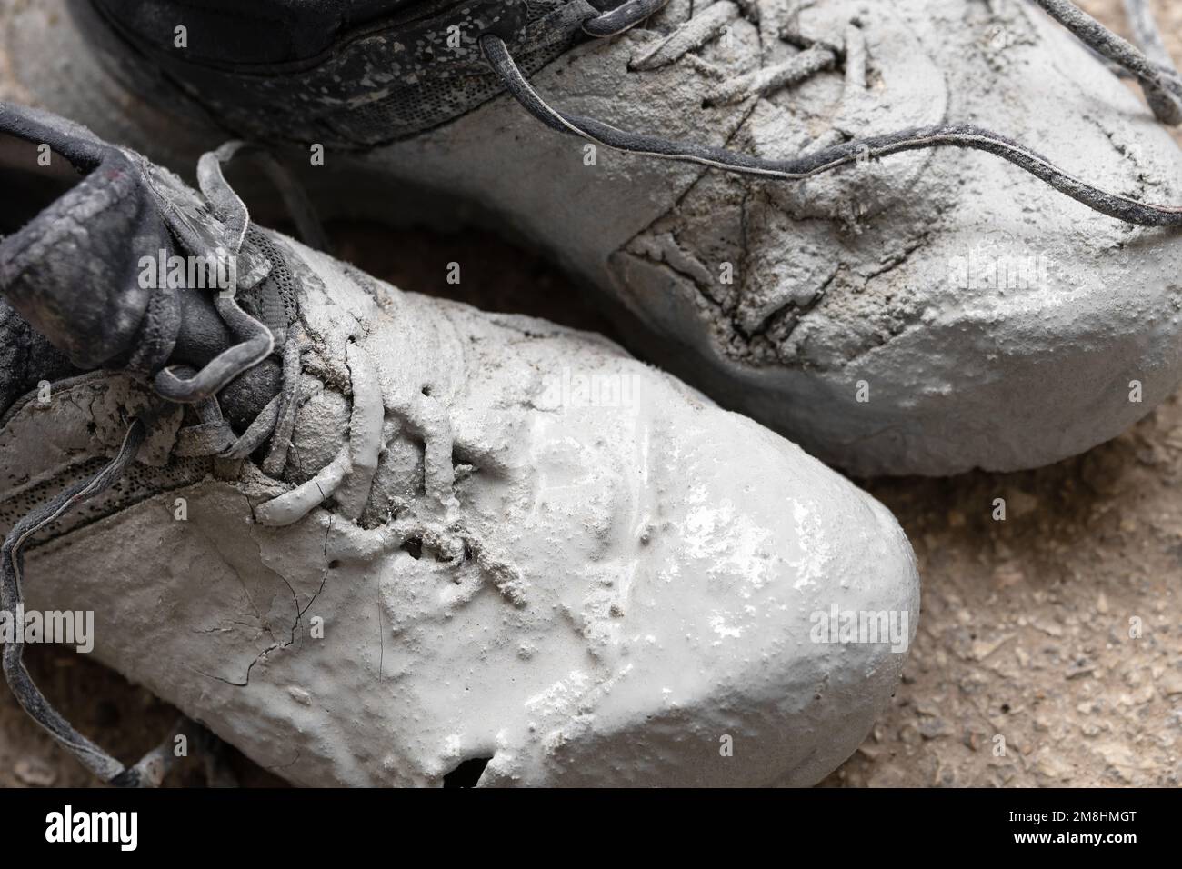 Chaussures fortement tachées dans la peinture grise sur un gros plan de l'asphalte Banque D'Images
