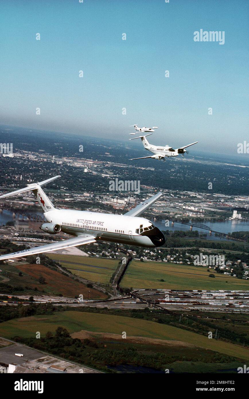 Une vue aérienne de trois quarts avant d'un avion C-9A Nightingale construit par McDonnell Douglas, avec un avion Beech construit C-12F et un Lear Jet construit C-21A volant de l'aile gauche du C-9. Tous les aéronefs proviennent de l'aile de transport aérien 375th, Air Mobility Command. Base: Scott Air Force base État: Illinois (il) pays: États-Unis d'Amérique (USA) Banque D'Images
