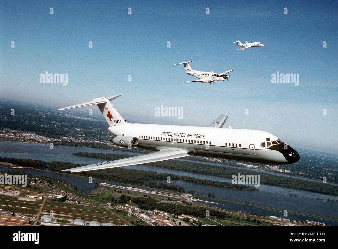 Une vue aérienne de trois quarts avant d'un avion C-9A Nightingale construit par McDonnell Douglas, avec un avion Beech construit C-12F et un Lear Jet construit C-21A volant de l'aile gauche du C-9. Tous les aéronefs proviennent de l'aile de transport aérien 375th, Air Mobility Command. Base: Scott Air Force base État: Illinois (il) pays: États-Unis d'Amérique (USA) Banque D'Images