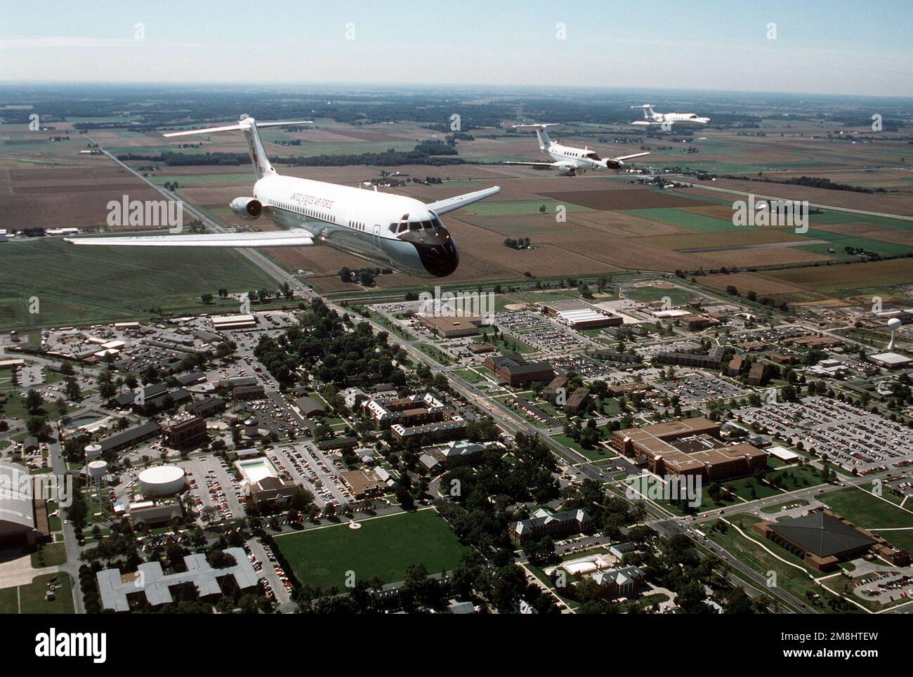 Vue aérienne de trois quarts avant d'un avion C-9A Nightingale construit par McDonnell Douglas, qui dirige une formation comprenant un C-12F et un C-21A sur la partie principale de la base et l'immeuble du Commandement de la mobilité aérienne du QG. Tous les aéronefs sont affectés à l'aile de transport aérien 375th, Air Mobility Command. Base: Scott Air Force base État: Illinois (il) pays: États-Unis d'Amérique (USA) Banque D'Images