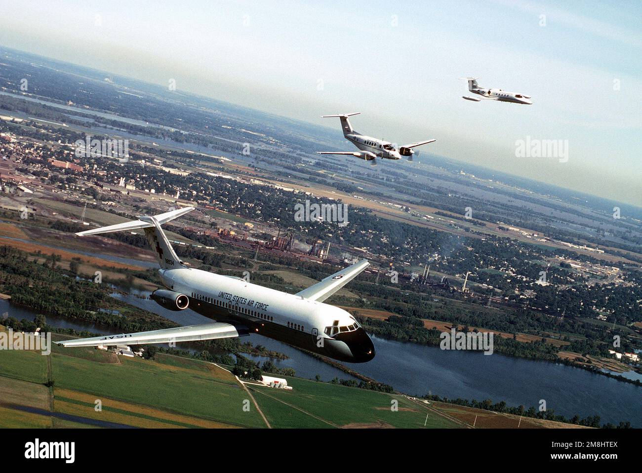 Une vue aérienne de trois quarts avant d'un avion C-9A Nightingale construit par McDonnell Douglas, avec un avion Beech construit C-12F et un Lear Jet construit C-21A volant de l'aile gauche du C-9. Tous les aéronefs proviennent de l'aile de transport aérien 375th, Air Mobility Command. Base: Scott Air Force base État: Illinois (il) pays: États-Unis d'Amérique (USA) Banque D'Images