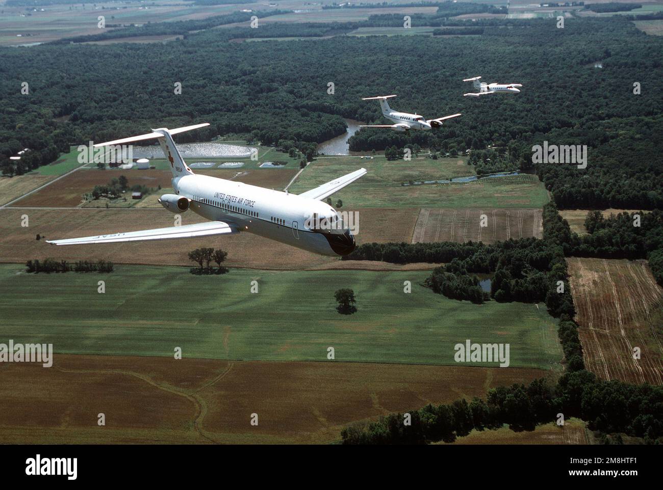 Une vue aérienne de trois quarts de l'avant d'un avion C-9A Nightingale construit par McDonnell Douglas, qui dirige une formation comprenant un C-12F et un C-21A au-dessus des terres agricoles près de la base. Tous les aéronefs sont affectés à l'aile de transport aérien 375th, Air Mobility Command. Base: Scott Air Force base État: Illinois (il) pays: États-Unis d'Amérique (USA) Banque D'Images
