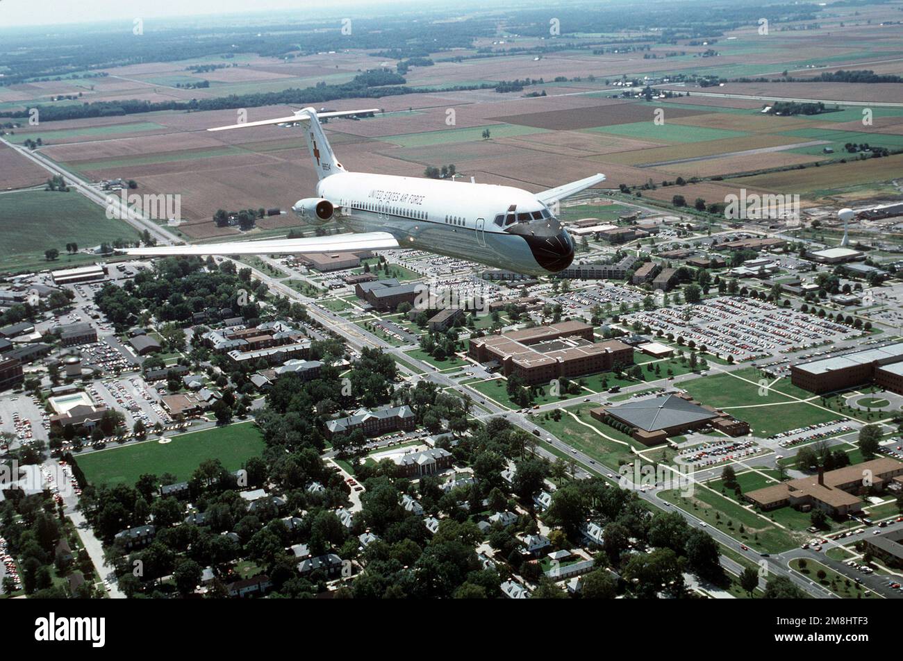 Vue aérienne de trois quarts d'un avion C-9A Nightingale construit par McDonnell Douglas survolant la partie principale de la base et l'immeuble du Commandement de la mobilité aérienne du QG. Le C-9A est affecté au Commandement de la mobilité aérienne de l'aile 375th du transport aérien. Base: Scott Air Force base État: Illinois (il) pays: États-Unis d'Amérique (USA) Banque D'Images