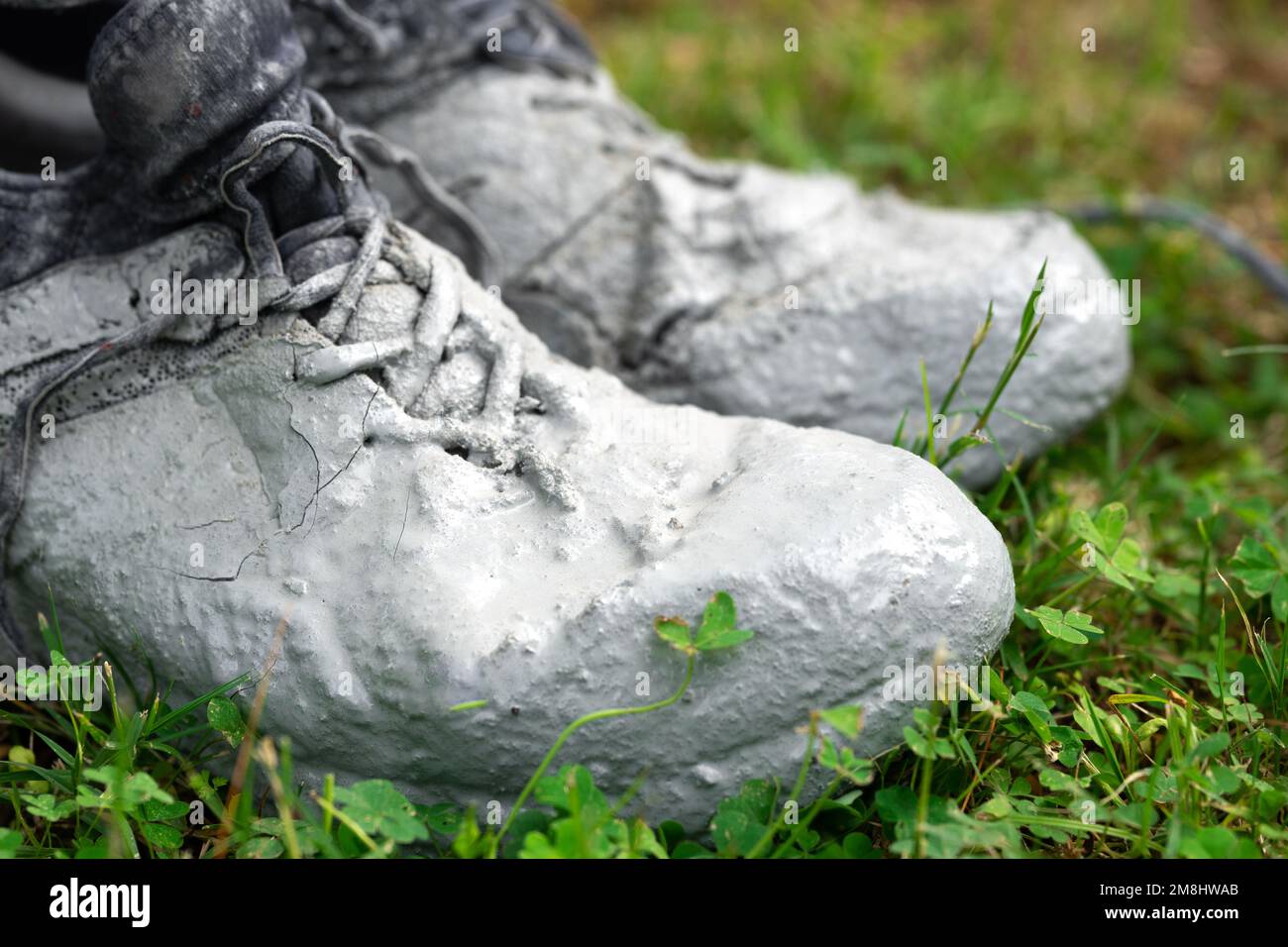Chaussures fortement tachées dans la peinture grise sur l'herbe verte Banque D'Images