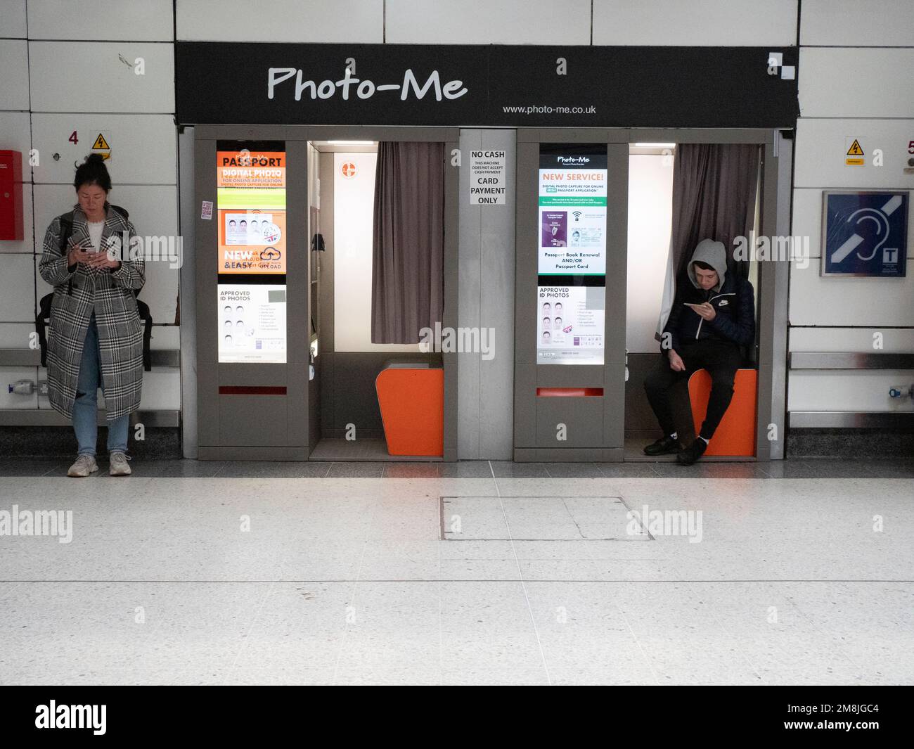 Photo-me passeport photo cabine, photo moi fait partie du groupe DE sociétés ME. Avec des gens qui regardent des téléphones mobiles en attendant des trains. Banque D'Images