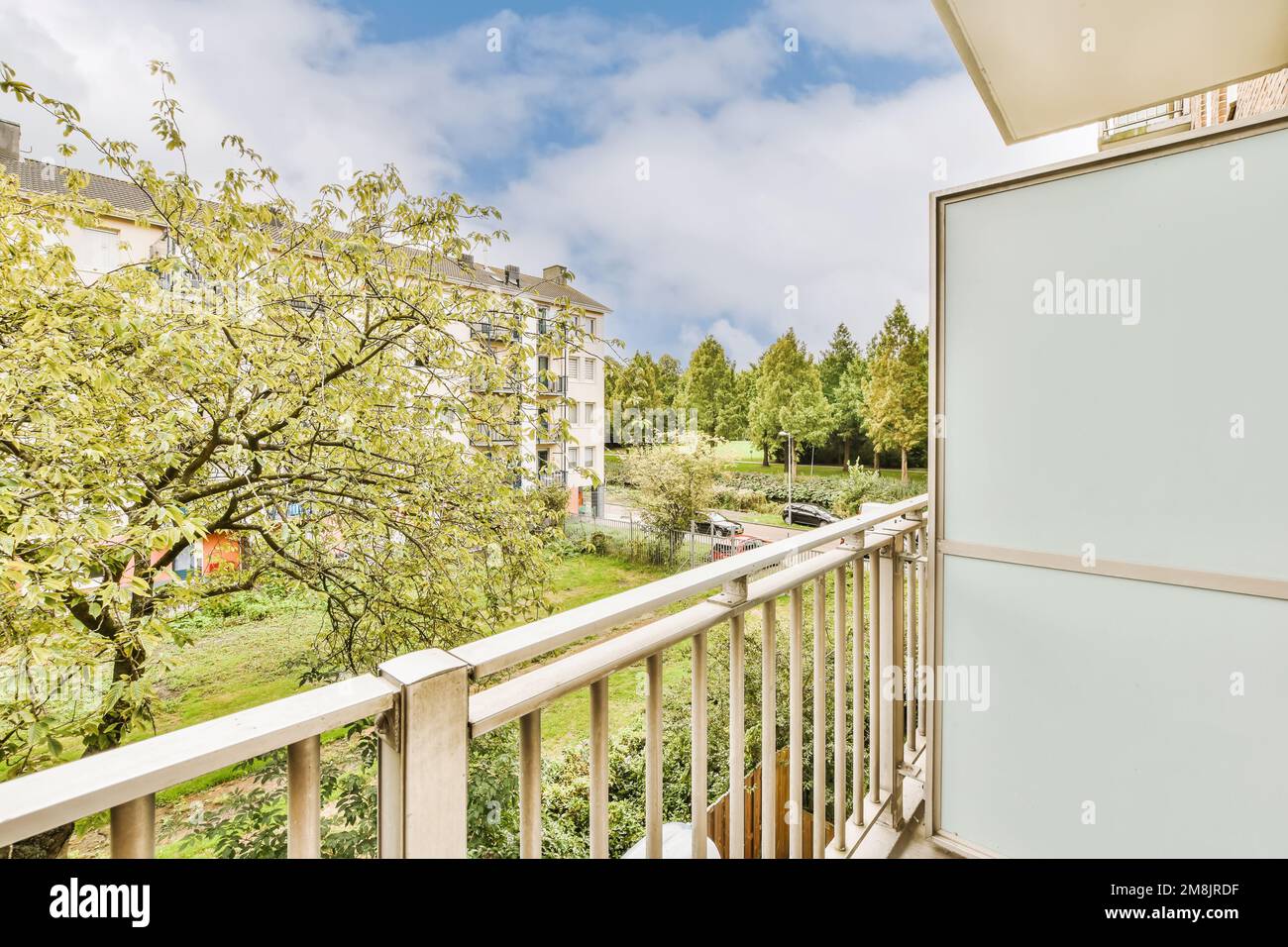 un balcon avec des arbres en arrière-plan et un ciel bleu au-dessus, vu d'un appartement balcon vue fenêtre Banque D'Images