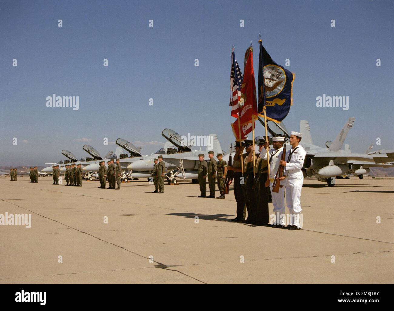 Un garde-couleurs conjoint de la Marine/Marine corps apporte les couleurs tandis que les équipages et les capitaines de VMFA(AW)-121 se tiennent devant leur avion lors d'une cérémonie d'arrivée qui s'est déroulée sur la ligne aérienne de la base aérienne navale Miramar pour VMFA(AW)-121 et l'escadron de réserve VMFA-134 qui s'est déplacé de la station aérienne du corps marin El Toro. Base : Naval Air Station, Miramar État : Californie (CA) pays : États-Unis d'Amérique (USA) Banque D'Images