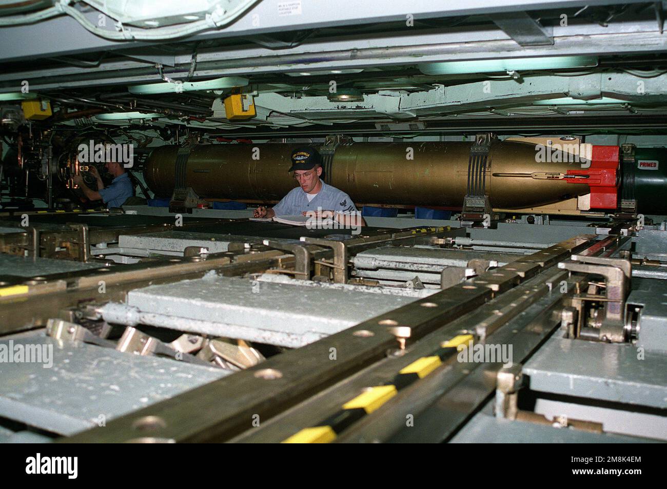 Fire Controlman First Class (FT1) Jeffery A. Girard ferme la porte du tube de torpille numéro un tandis qu'un torpille de première classe effectue un inventaire des armes à bord du sous-marin d'attaque nucléaire USS LOUISVILLE (SSN-724). Une torpille d'entraînement est fixée à la cloison tribord. Pays : Océan Pacifique (POC) Banque D'Images