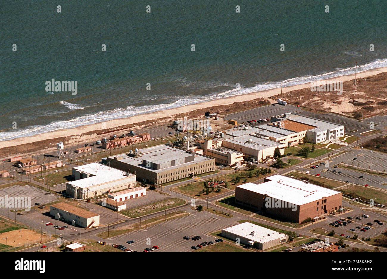 Vue aérienne du bâtiment d'essai du Naval surface Warfare Center sur la base navale de Dam Neck. Le long de la plage sont différents types de supports de canon avec leurs radars de contrôle d'incendie associés au sommet du bâtiment d'essai. Base: Dam Neck État: Virginie (va) pays: Etats-Unis d'Amérique (USA) Banque D'Images
