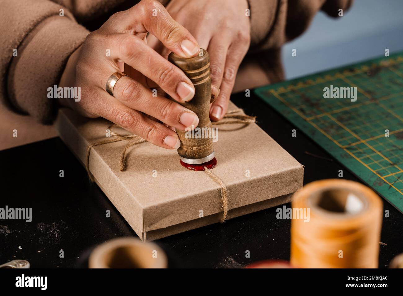 CRAFTSMAN met un timbre sur la cire d'étanchéité sur les cadeaux faits à la main dans l'atelier. Procédé de scellement de cire sur l'emballage cadeau en atelier Banque D'Images