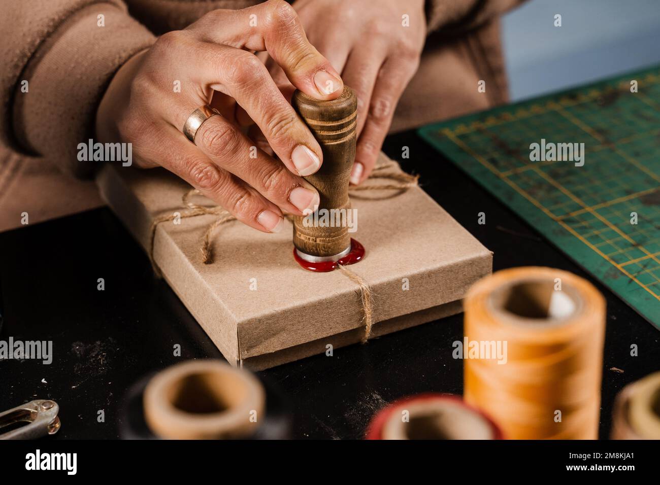 CRAFTSMAN met un timbre sur la cire d'étanchéité sur les cadeaux faits à la main dans l'atelier. Procédé de scellement de cire sur l'emballage cadeau en atelier Banque D'Images