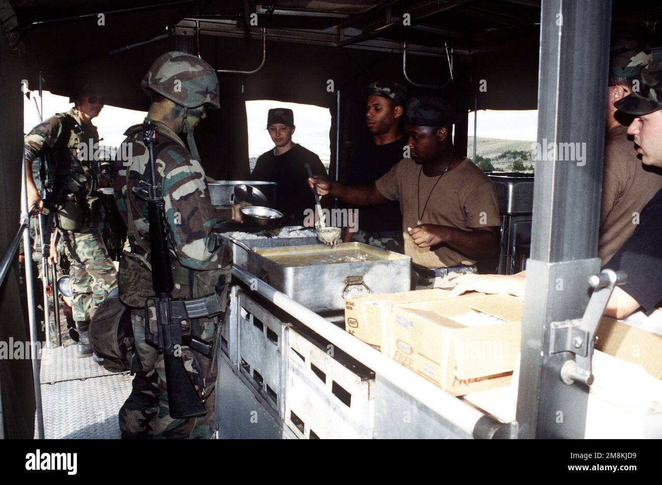 Sous la bâche de la cuisine mobile de terrain de l'escadron de services 341st, l'AVIATEUR Jessyca hilar, LE PERSONNEL SGT. Nyron Alexander et L'AVIATEUR PRINCIPAL Robert Hadley servent de chow à chaud à L'AVIATEUR Michael Morgan II, 564th missile Squadron, tandis que L'AVIATEUR PRINCIPAL Robert Joel et d'autres membres attendent leur tour dans la file. Objet opération/série: MARAUDER 1995 base: Calcaire Hills État: Montana (MT) pays: États-Unis d'Amérique (USA) Banque D'Images