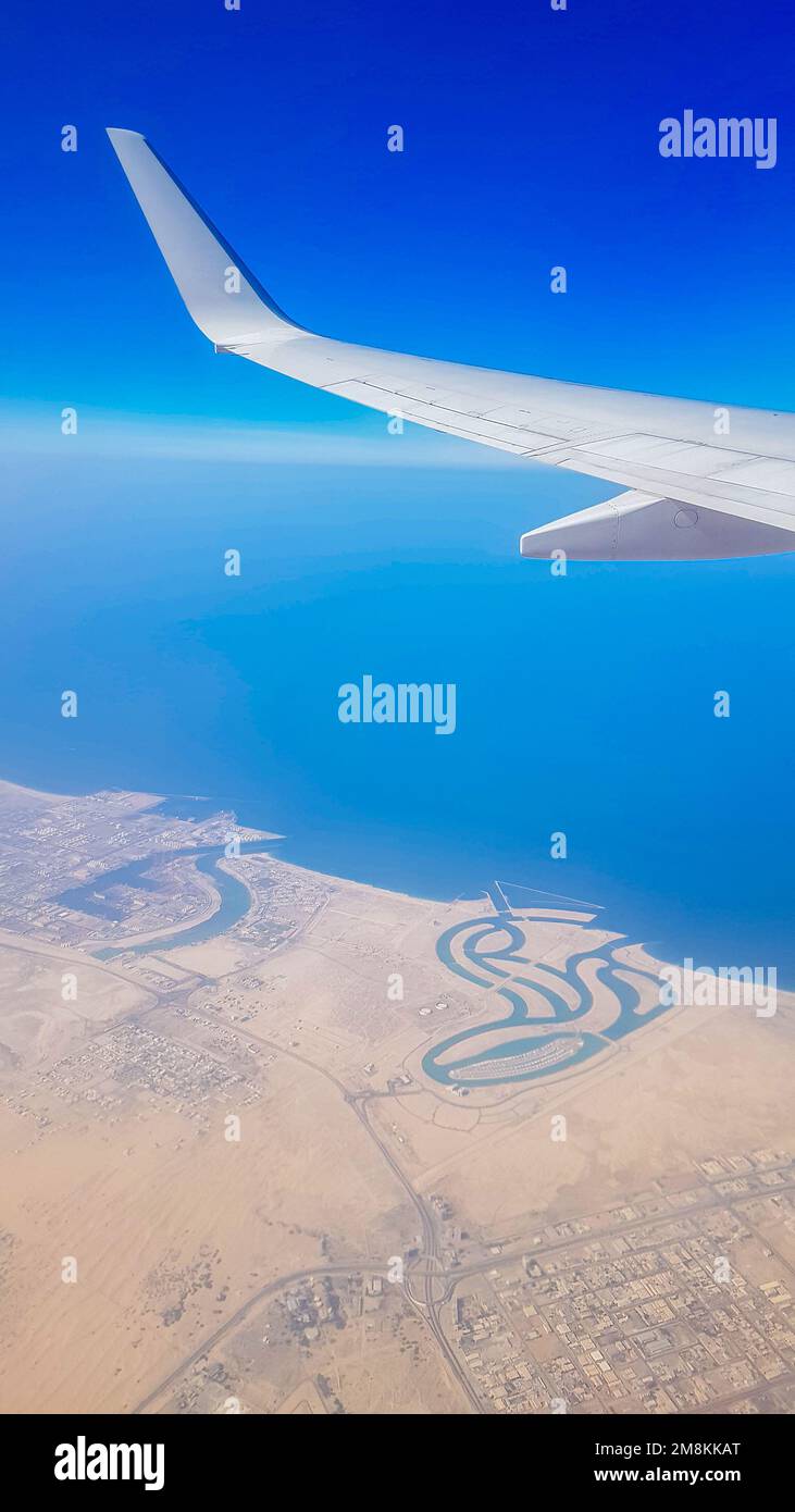 Vue de la fenêtre de l'avion sur le ciel bleu et la terre avec paysage de désert, mer et canaux dans les Émirats. Photo de haute qualité Banque D'Images