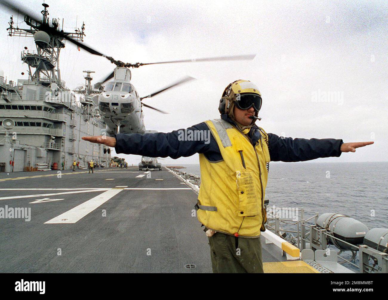 970621-N-5121B-015. [Complete] Scene Caption: Aviation Boatswains Mate troisième classe Curtis Rowe dirige un hélicoptère marin du Marine Medium Helicopter Squadron 163 au large du pont de vol USS TARAWA (LHA 1) pendant l'exercice KERNEL BLITZ '97 qui a lieu au large de la côte sud de la Californie et Camp Pendleton. Les hélicoptères Sea Knight CH-46E sont vus en arrière-plan. KERNEL BLITZ est un exercice semestriel d'entraînement de la flotte du commandant en CHEF du Pacifique (CINCPAC) (FLEETEX) axé sur l'entraînement opérationnel/tactique du commandant de la troisième flotte (C3F)/ I Marine Expeditionary Forces (MEF) et du commandant, Amphibie Banque D'Images