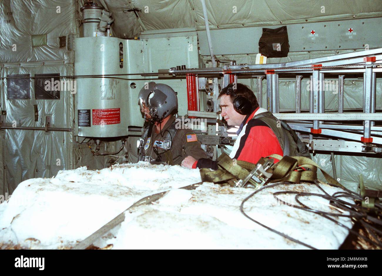 Bill Redmond (à droite), membre du Congrès du Nouveau-Mexique en 3rd, regarde le SMSGT David Furr, chargé de charge avec l'aile 185th du transport aérien, Will Rogers Air National Guard base, Oklahoma City, Oklahoma, libère 1 800 livres de foin de l'avion C-130 Hercules pour le bétail en panne après un blizzard lourd. État: Nouveau Mexique (NM) pays: Etats-Unis d'Amérique (USA) Banque D'Images