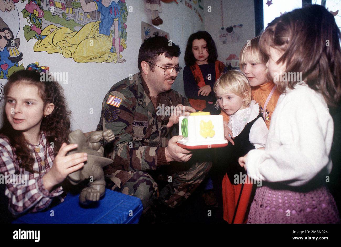 SERGENT d'ÉTAT-MAJOR de la Force aérienne des États-Unis Patrick Gibbens, réparateur radio terrestre et affecté au 18th EAGLE Air support Operations Squadron, à la base Eagle Tuzla, en Bosnie-Herzégovine, Montre à certains des enfants vivant au Centre mère et enfant réfugiés de Simin Han comment utiliser un jouet. Gibbens, ainsi que des membres du groupe de la base aérienne expéditionnaire 401st de la base aérienne de Tuzla, se sont portés volontaires pour offrir des dons de jouets, de nourriture et de vêtements, afin d'aider les personnes vivant dans le centre des réfugiés. Le centre abrite des réfugiés de Srebrenica, dont les pères ont été tués ou disparus des Balkans C. Banque D'Images