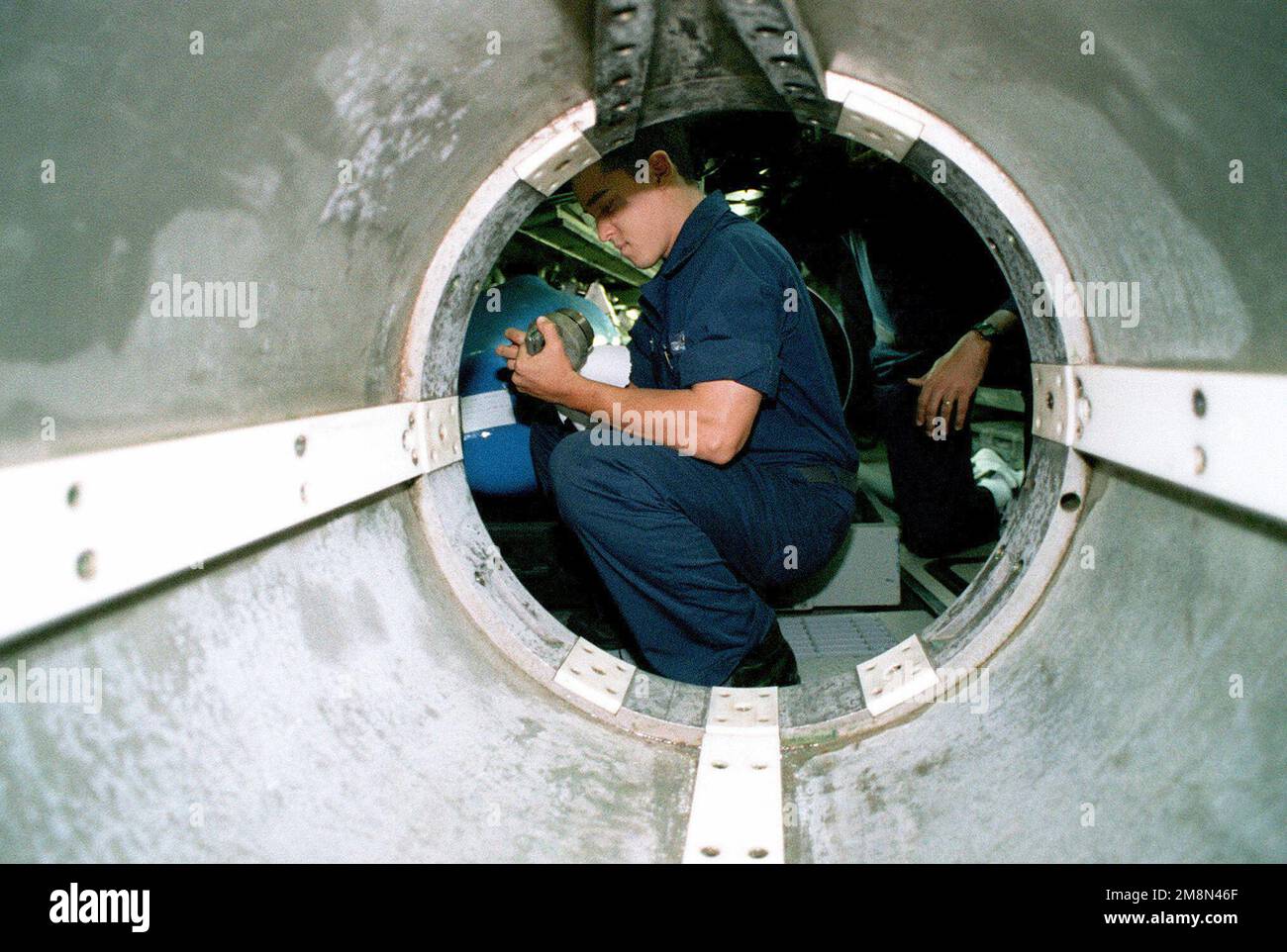 LE MACHINISTE américain Mate Fireman (MNPF) Brian Zitt vérifie une porte de tube de torpille à bord du sous-marin d'attaque USS TUCSON (SSN 770). Le TUCSON est déployé dans le golfe Persique à l'appui de l'opération SOUTHERN WATCH, 19 mai 1998. Objet opération/série : BASE DE MONTRE DU SUD : USS Tucson (SSN 770) Banque D'Images