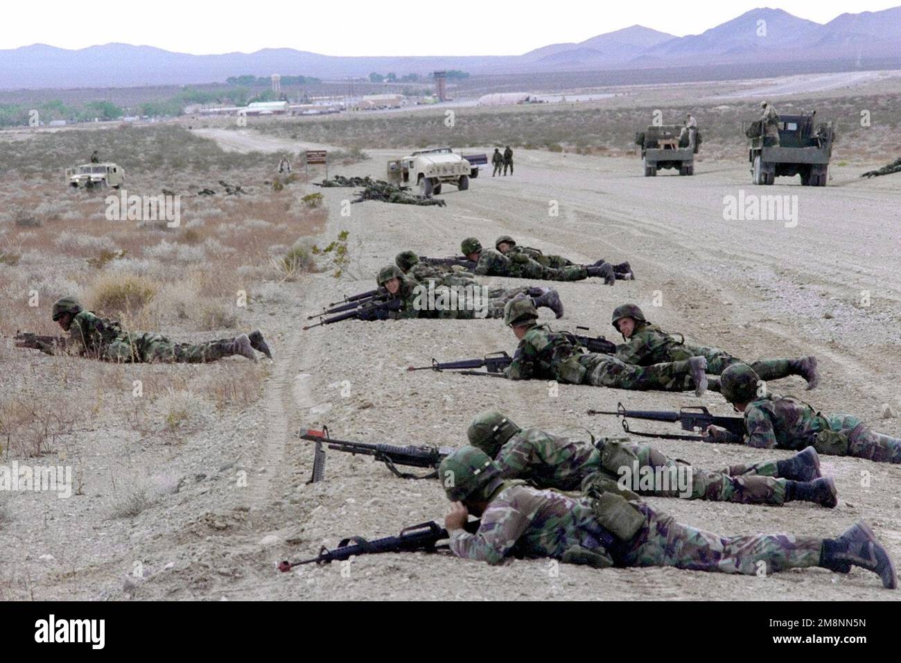 Les membres de l'escadron 169th de la police de sécurité, de la Garde nationale aérienne de Caroline du Sud, de la base de la Garde nationale aérienne McEntyre, en Caroline du Sud, déployés à Indian Springs Air Force Auxiliary Field, Nevada, assument des positions défensives à côté d'une route de gravier. Le personnel est armé de fusils de 5,56 mm M16 et d'une mitrailleuse de 7,62 mm M60, tous dotés de pièces de tir vierges. Les véhicules en arrière-plan comprennent le véhicule polyvalent à roues haute mobilité M1025 (HMMWV), 23 avril 1999. Base: Indian Springs Auxiliary Field État: Nevada (NV) pays: Etats-Unis d'Amérique (USA) Banque D'Images