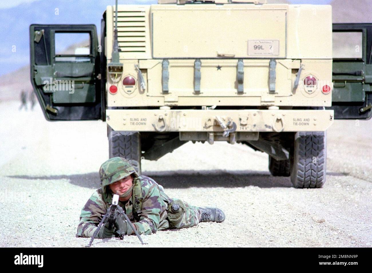 Un membre de l'escadron de la police de sécurité 169th, Garde nationale aérienne de Caroline du Sud, base de la Garde nationale aérienne McEntyre, Caroline du Sud, déployé à Indian Springs Air Force Auxiliary Field, Nevada, assume une position défensive en décubitus ventral avec une mitrailleuse de 7,62 mm M60, équipée d'obturateurs de feu, Un véhicule polyvalent à roues haute mobilité M1025 (HMMWV) stationné en arrière-plan, le 23 avril 1999. Base: Indian Springs Auxiliary Field État: Nevada (NV) pays: Etats-Unis d'Amérique (USA) Banque D'Images