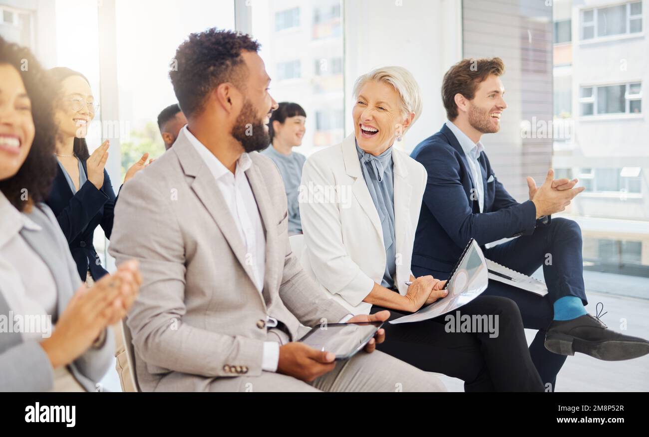 Gaie femme d'affaires caucasienne mûre en riant avec un collègue lors d'une présentation dans un bureau. Femme dans le public souriant tout en écoutant Banque D'Images