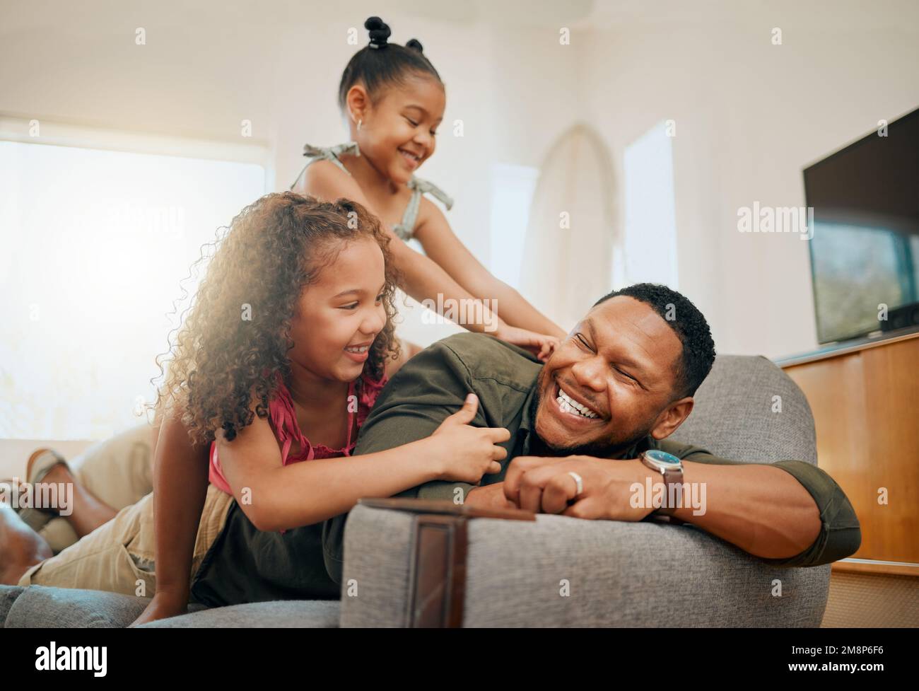 Une famille de trois personnes se détendant dans le salon et jouant ensemble. Aimant parent unique noir liant avec ses filles pendant Banque D'Images