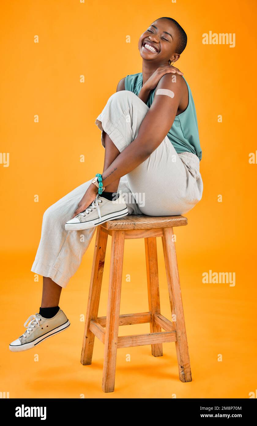 Femme vaccinée Covid afro-américaine montrant du plâtre sur le bras et souriant. Modèle noir sur toute la longueur isolé sur fond de studio jaune avec Banque D'Images