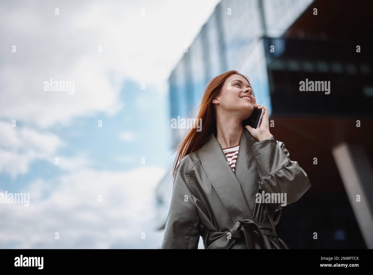 Femme d'affaires parlant au téléphone et souriant avec des dents sur le fond de la ville bâtiments, la technologie et le développement d'affaires concept en ligne Banque D'Images