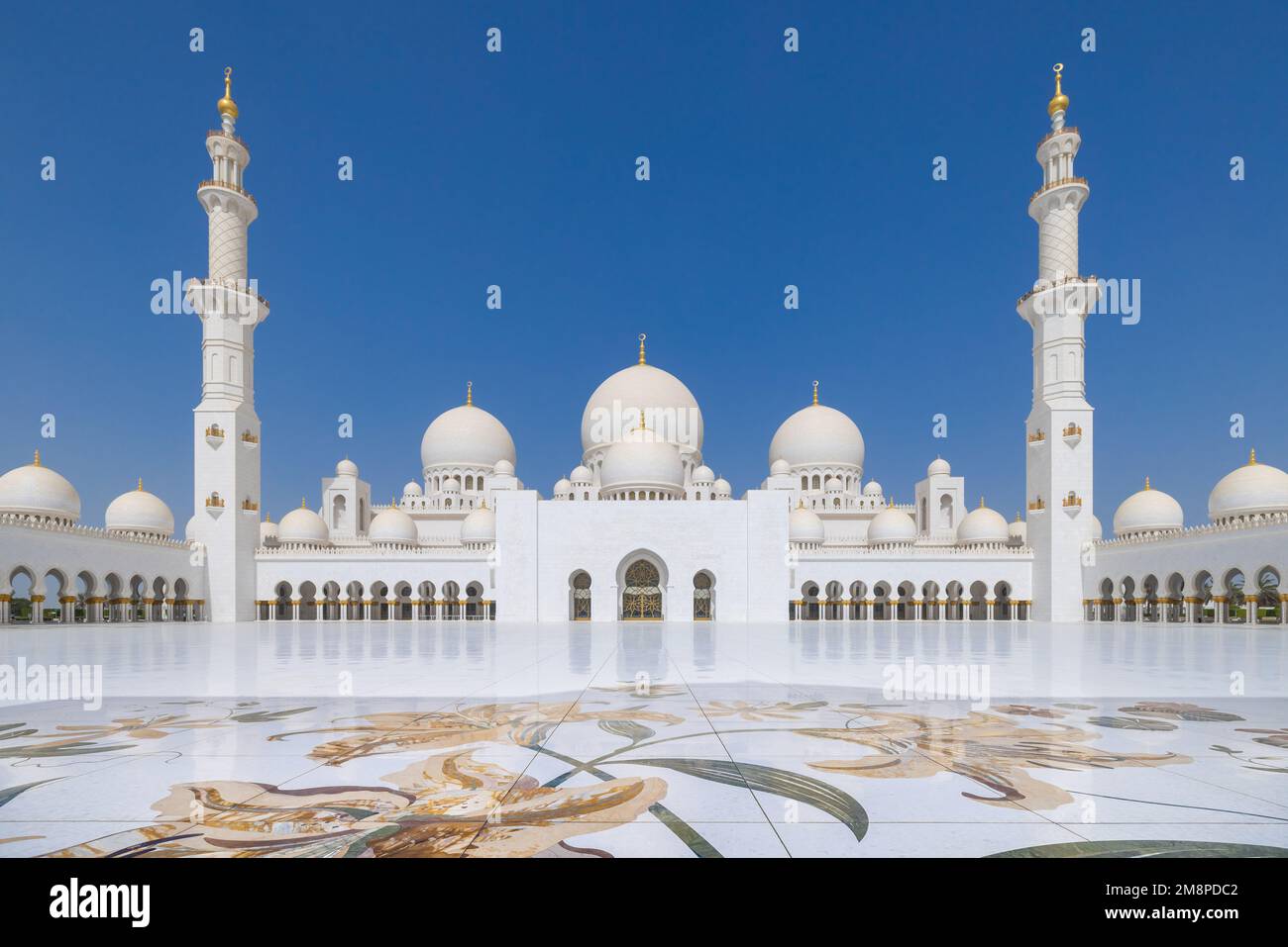 Vue symétrique de la cour principale de la grande mosquée Sheik Zayed à Abu Dhabi avec la salle de prière flanquée de minaret à l'extrémité Banque D'Images