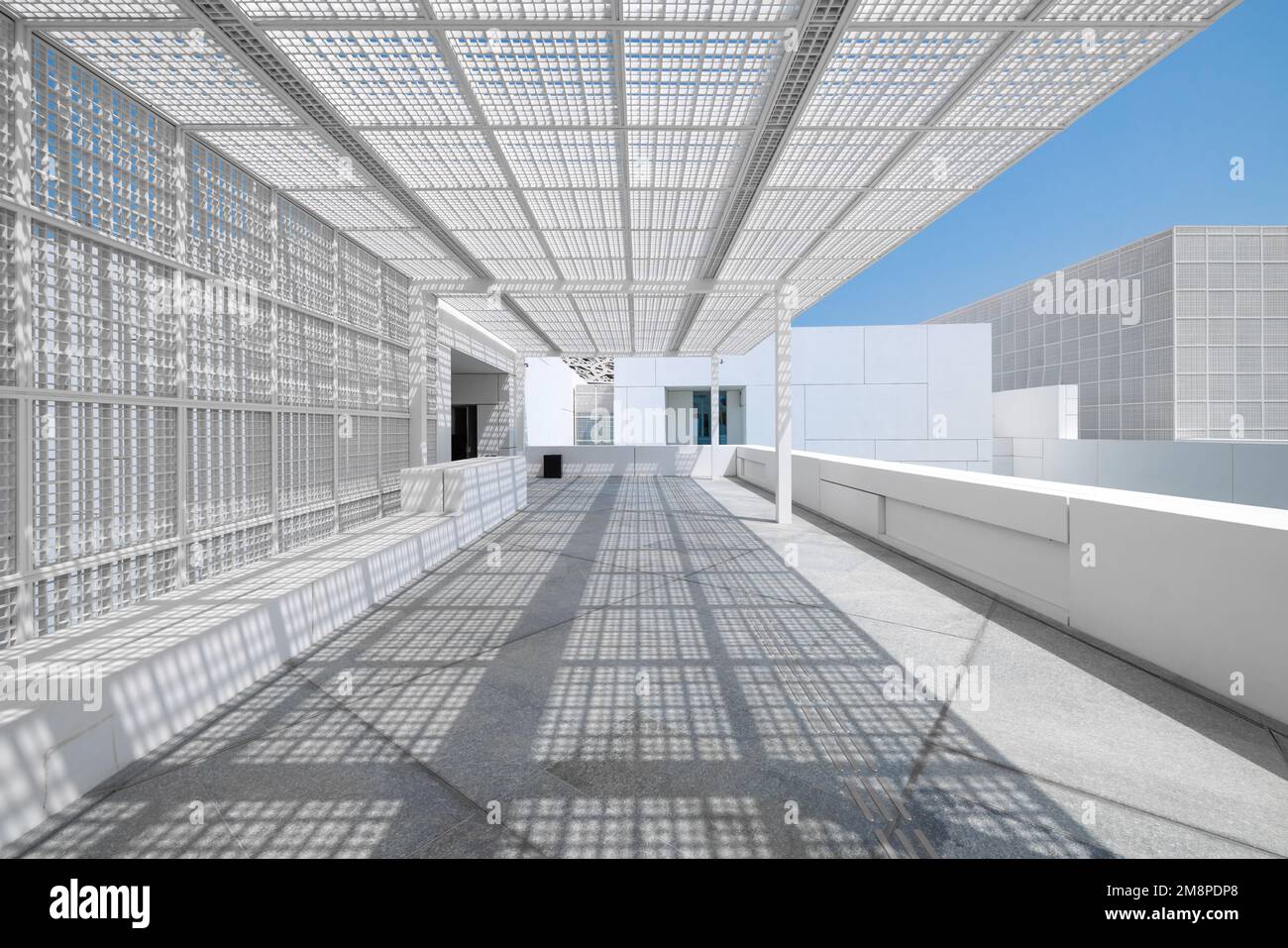 L'entrée moderne du musée du Louvre d'Abu Dhabi, avec une passerelle en marbre blanc et une grille géométrique carrée en métal pour l'ombre Banque D'Images