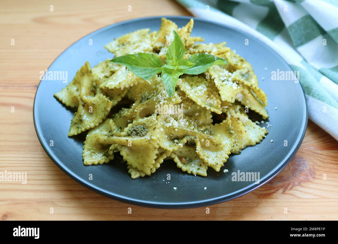 Une assiette de pâtes farfalle ou Bow-tie en sauce pesto servie sur une table en bois Banque D'Images