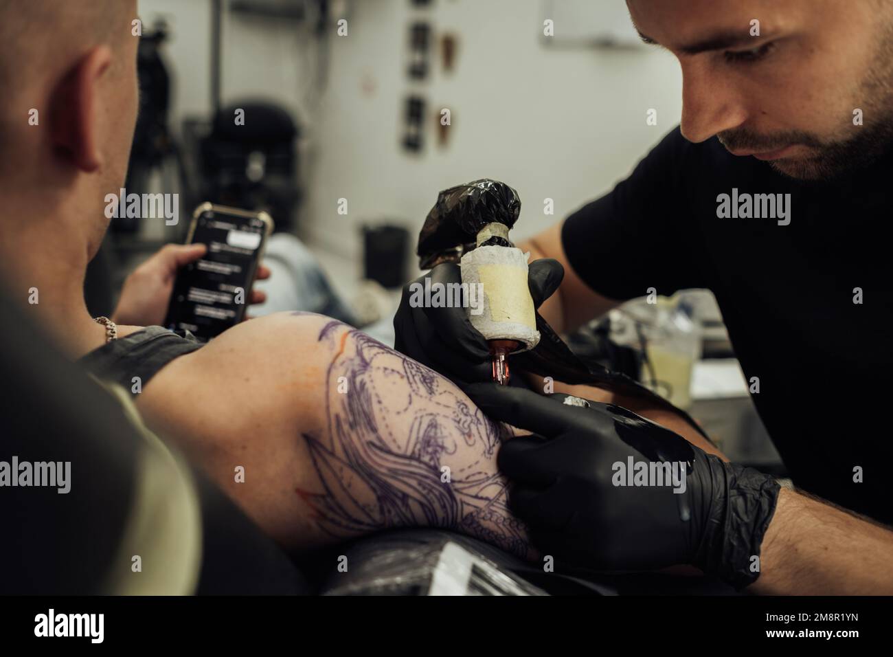 L'artiste de tatouage masculin s'inspire de la peau du client, processus de création de l'art de tatouage Banque D'Images