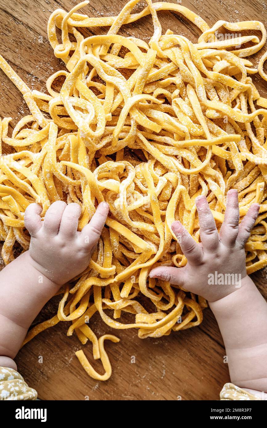 Pâtes et enfant. Bébé cuisine des pâtes fraîches italiennes dans la cuisine maison. Nourriture et enfants concept. Photo de haute qualité Banque D'Images