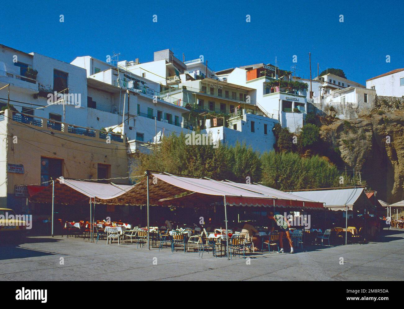Image d'archivage. Les auvents fournissent de l'ombre pour les tables d'un café au bord de l'eau à Agia Galini dans le sud de la Crète 1979 Banque D'Images