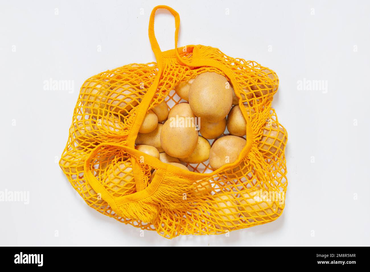 Sac réutilisable en filet avec pommes de terre fraîches. Sac à ficelle orange. Pommes de terre crues. Vue de dessus. Végétarien, aliments crus, légumes frais. Consommation consciente Banque D'Images